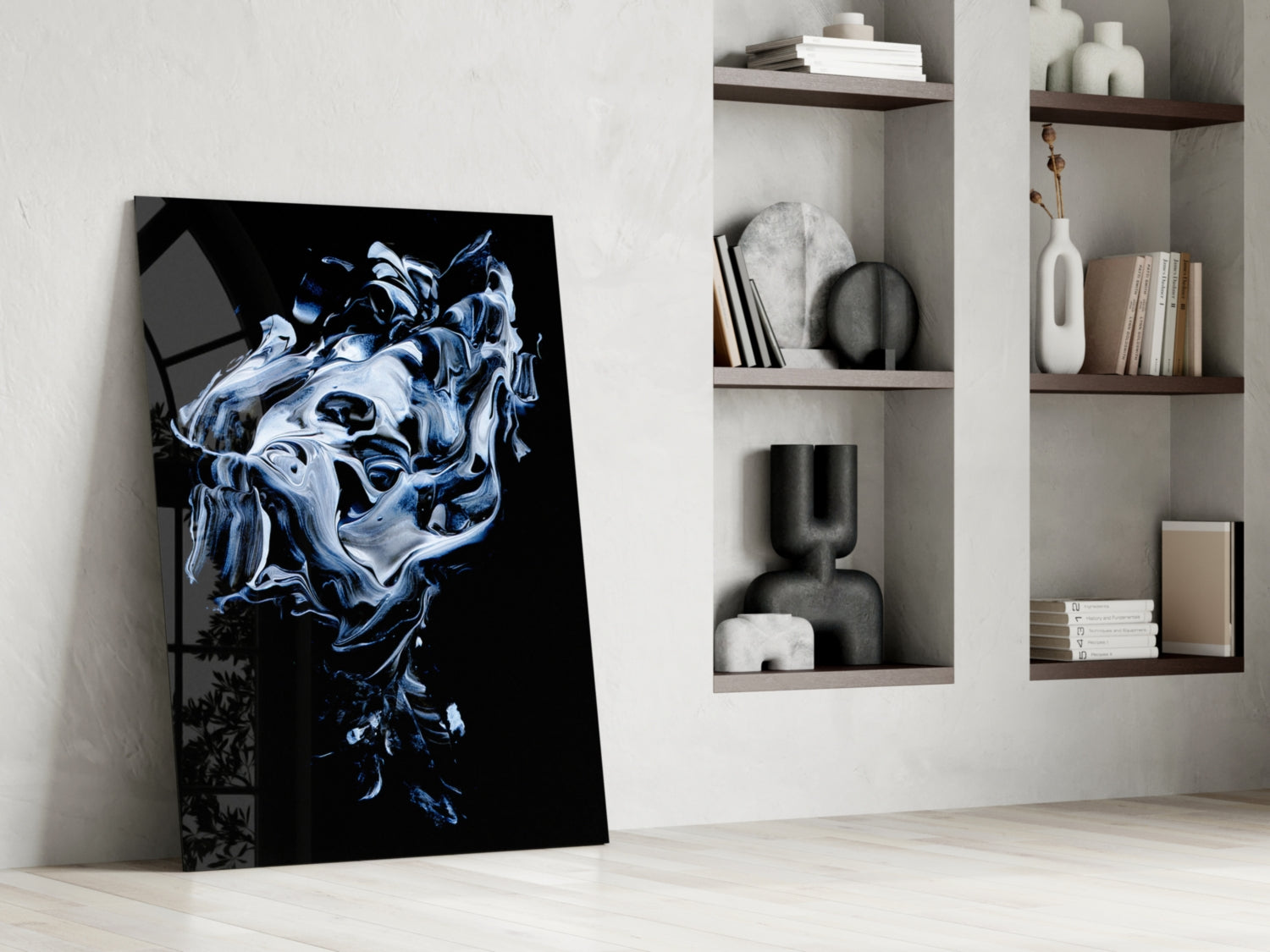 Abstract gray glass wall art leaning against white wall beside shelving unit displaying books and decorative objects.