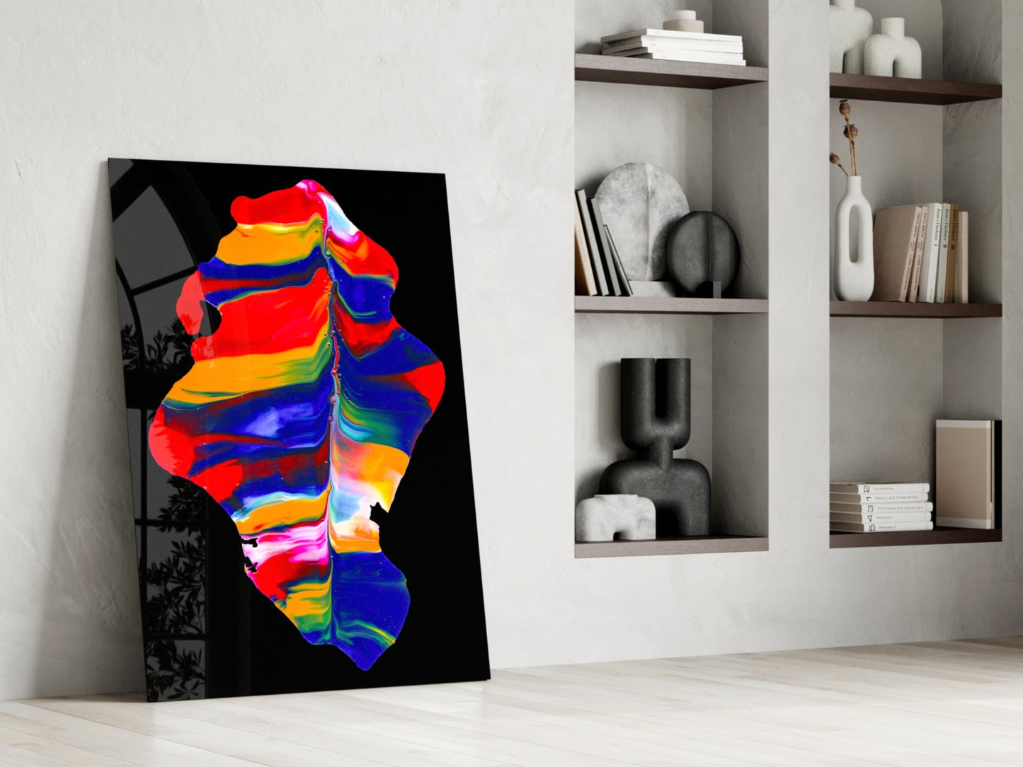 Colorful thermal art glass leaning against white wall beside shelving unit holding books and decorative objects.