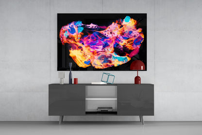 Vibrant abstract glass wall art displaying neon pink, orange, cyan, and blue swirling patterns mounted above a gray media console.