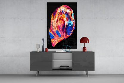 Vibrant thermal-map style glass art with red, orange, pink, and blue hues displayed above a gray media console in a modern interior setting.