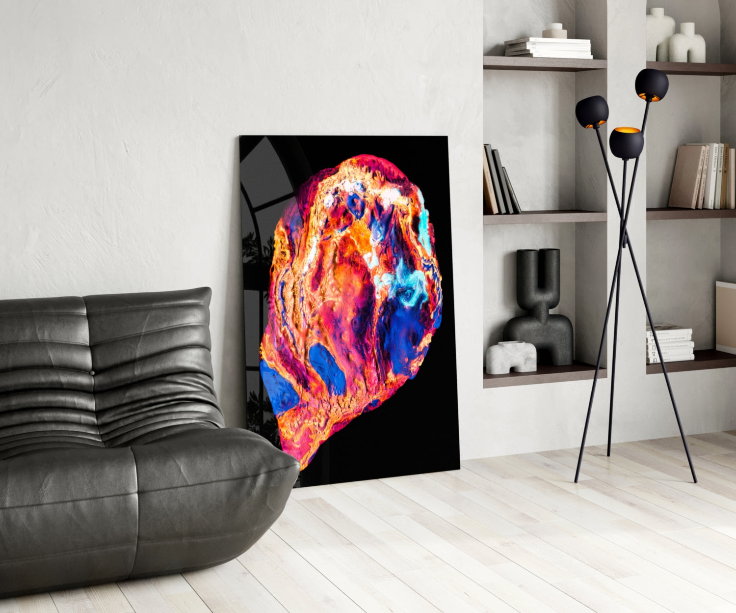 Colorful lava glass wall art with vibrant orange, red, pink, blue, and yellow swirls displayed in a modern living room next to a gray leather chair.