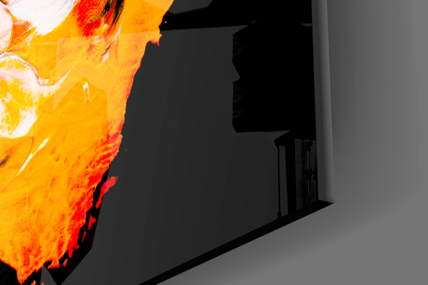 Close-up of vibrant yellow and orange glass wall art with red accents mounted on gray wall interior.