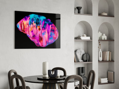 Vibrant neon pink and blue glass wall art displayed above a black dining table in a modern interior with built-in shelving.