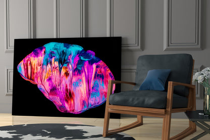 Vibrant neon pink and cyan abstract glass art displayed on black background in modern living room setting.