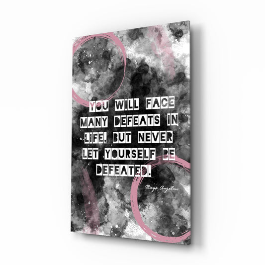 Glass wall art panel with black and white watercolor background, pink circular brushstrokes, and white block text quote attributed to Maya Angelou.