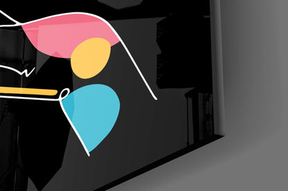 Colorful abstract glass wall art with pink, yellow, and blue hand shapes installed on dark interior wall.