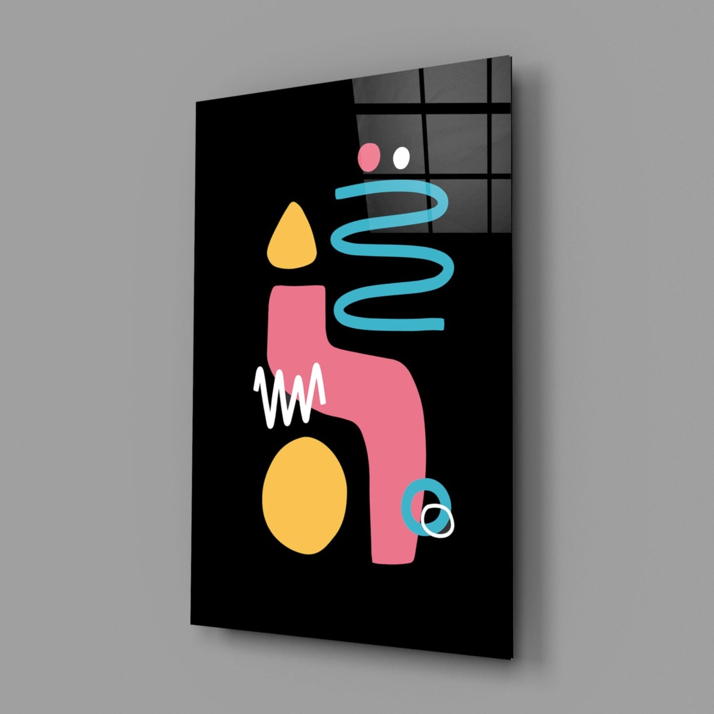 Angled view of black glass wall art featuring colorful abstract candle design with pink, yellow, and blue shapes against a gridded window background.