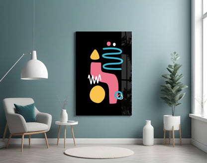 Modern living room with abstract black canvas featuring pink, yellow, and blue geometric shapes hung above a cream armchair beside potted plants.