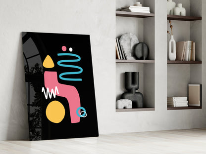 Abstract black canvas with pink, yellow, and blue geometric shapes leaning against white wall with built-in shelving.