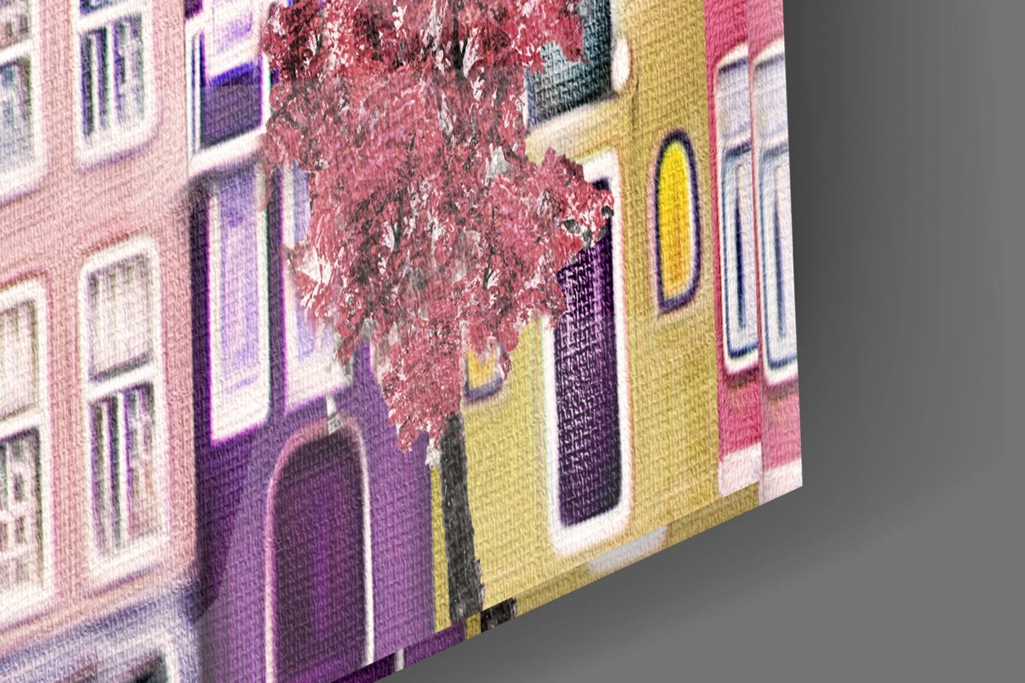 Close-up angled view of glass wall art showing colorful townhouses in pink, purple, and yellow with ivy-covered building and white-framed windows.