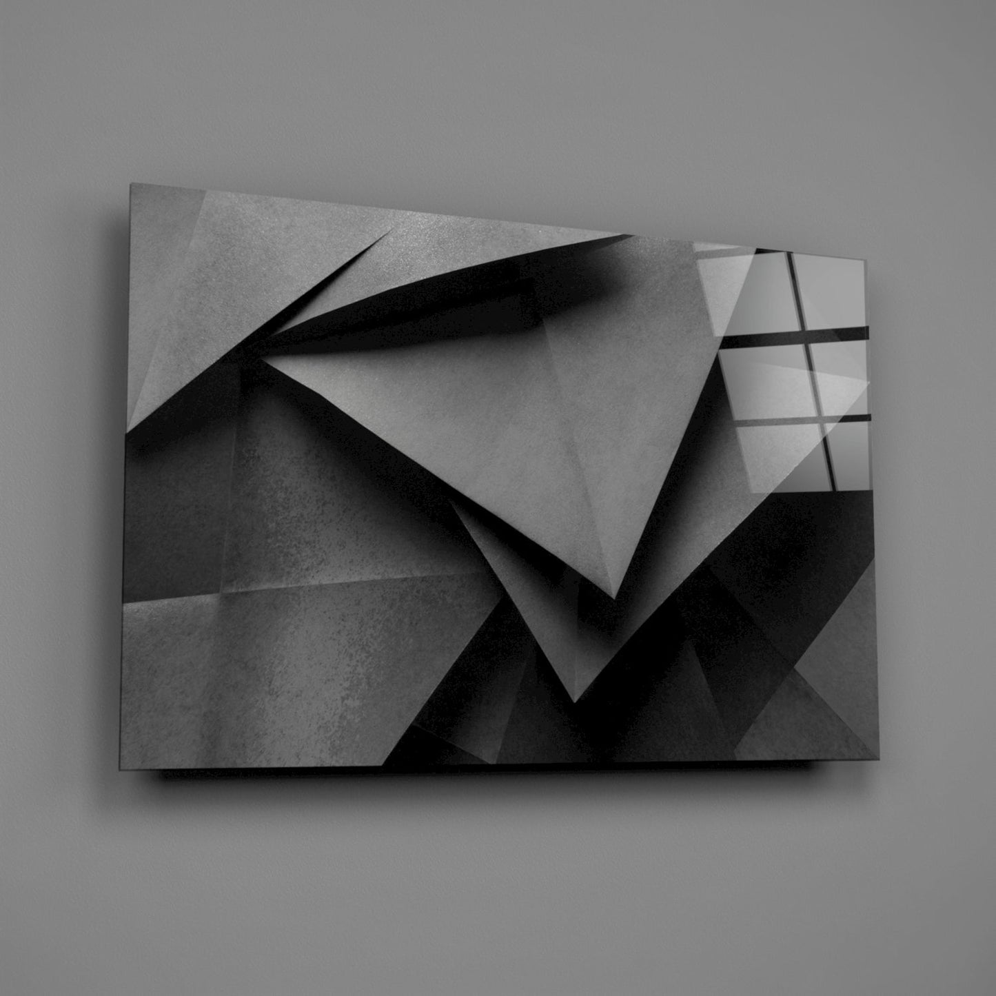 Monochromatic glass wall art displaying overlapping geometric planes with sharp shadows and gradated grayscale tones on neutral background.