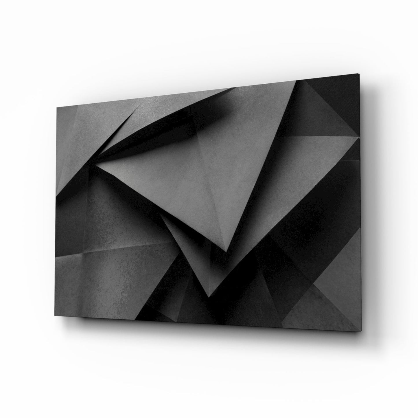 Angled perspective view of black and gray geometric glass wall art with folded paper-like relief pattern and shadow details.