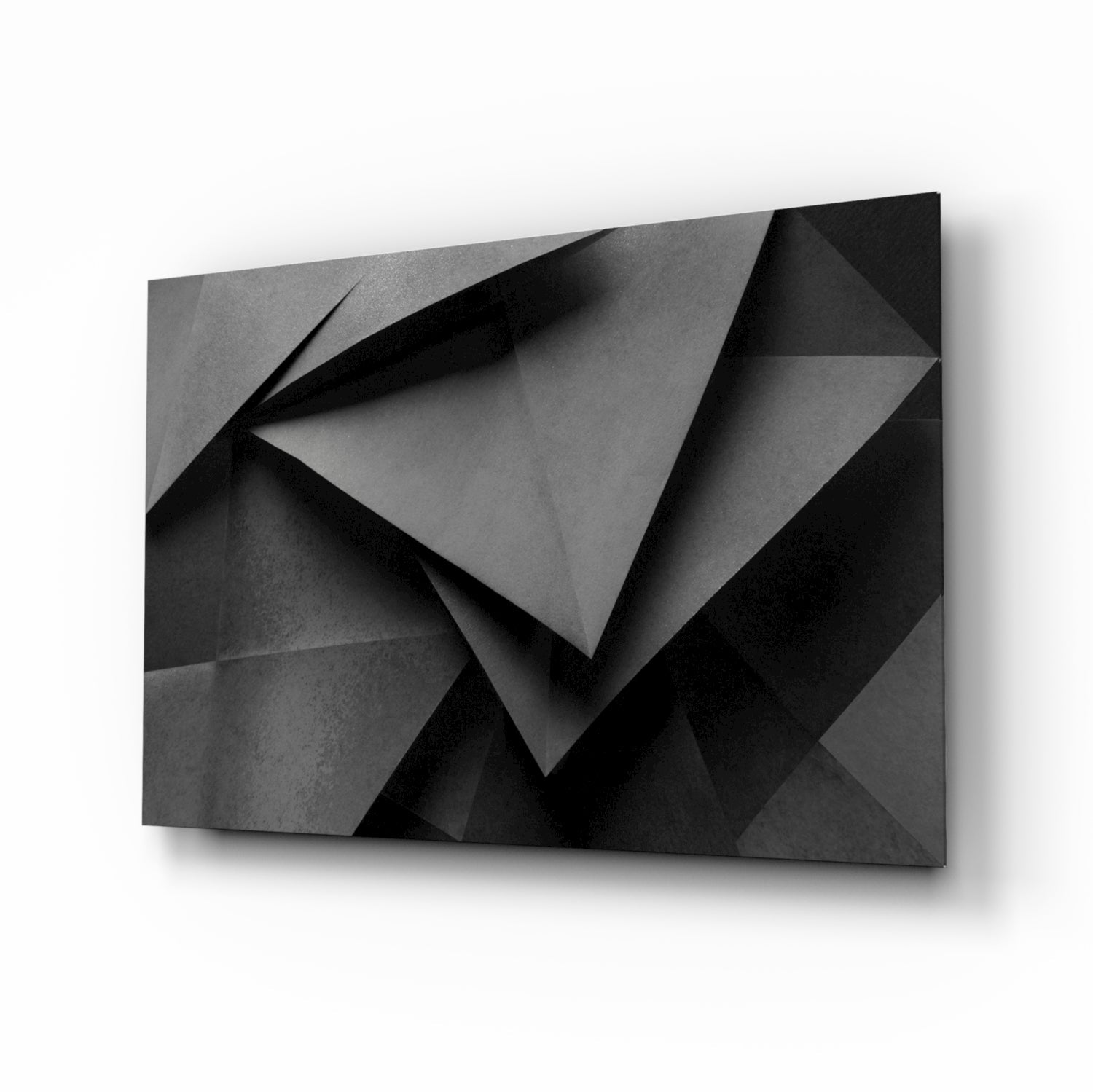 Angled perspective view of black and gray geometric glass wall art with folded paper-like relief pattern and shadow details.