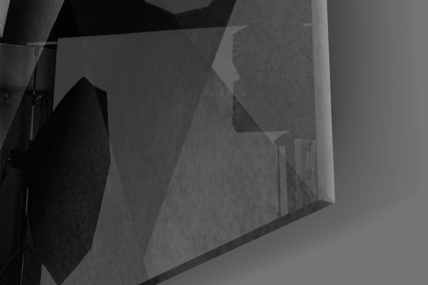Close-up angled view of frosted glass wall art panel with geometric layered design in grayscale tones.