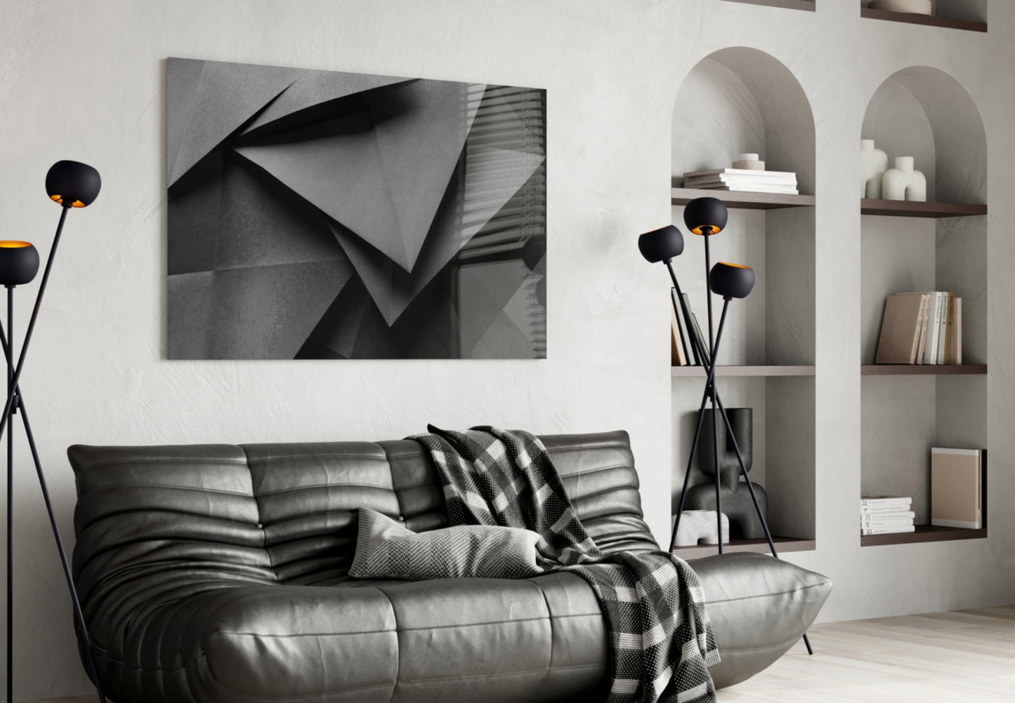 Modern living room featuring a black leather sofa with a geometric grayscale wall art print above it and arched wall shelving.