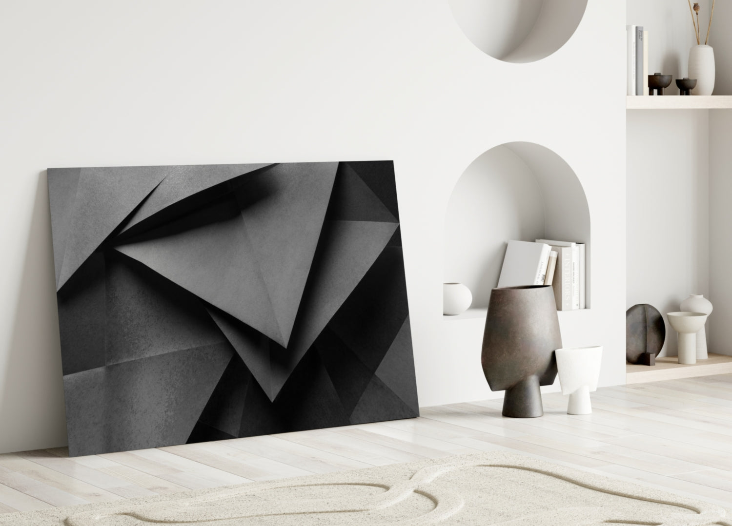 Modern minimalist interior showroom featuring black geometric glass wall art leaning against white wall beside neutral decorative objects.