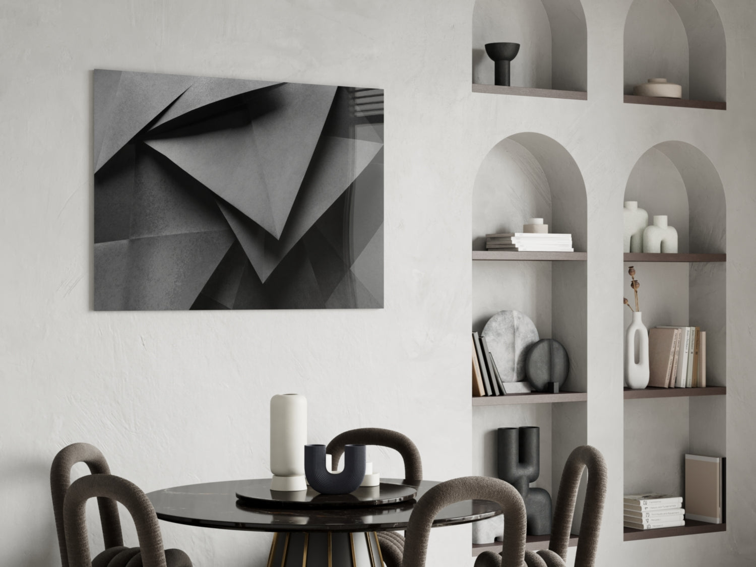 Monochromatic geometric abstract wall art with folded paper shapes displayed above a round black dining table in a minimalist interior.
