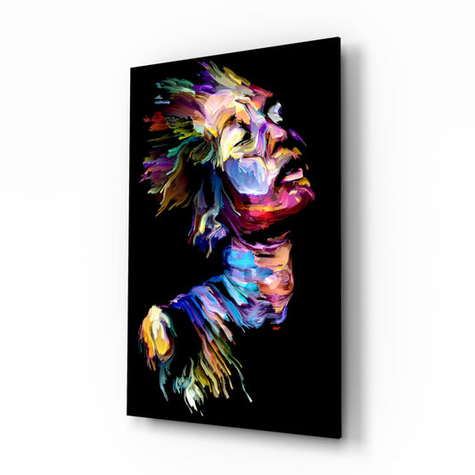 Angled side view of a glass wall art panel displaying a colorful abstract portrait with vibrant rainbow paint strokes on black background.