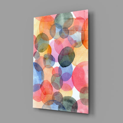Angled view of rectangular glass wall art displaying overlapping watercolor circles in pink, orange, blue, yellow, and green on white background.