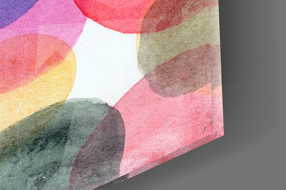Angled view of watercolor glass wall art displaying overlapping circular washes in pink, red, yellow, green, and brown tones on white background.