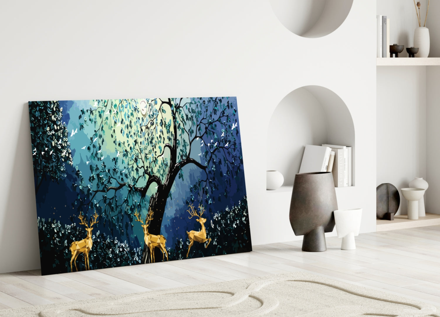 Golden Deers Glass Wall Art leaning against white wall in minimalist room with blue-toned forest and golden deer design.