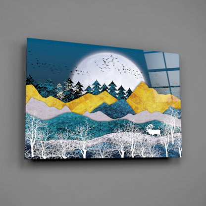 Textured glass wall art depicting layered mountains in yellow and teal with white birch trees, a full moon, and an elk, displayed at an angle against a gray wall.