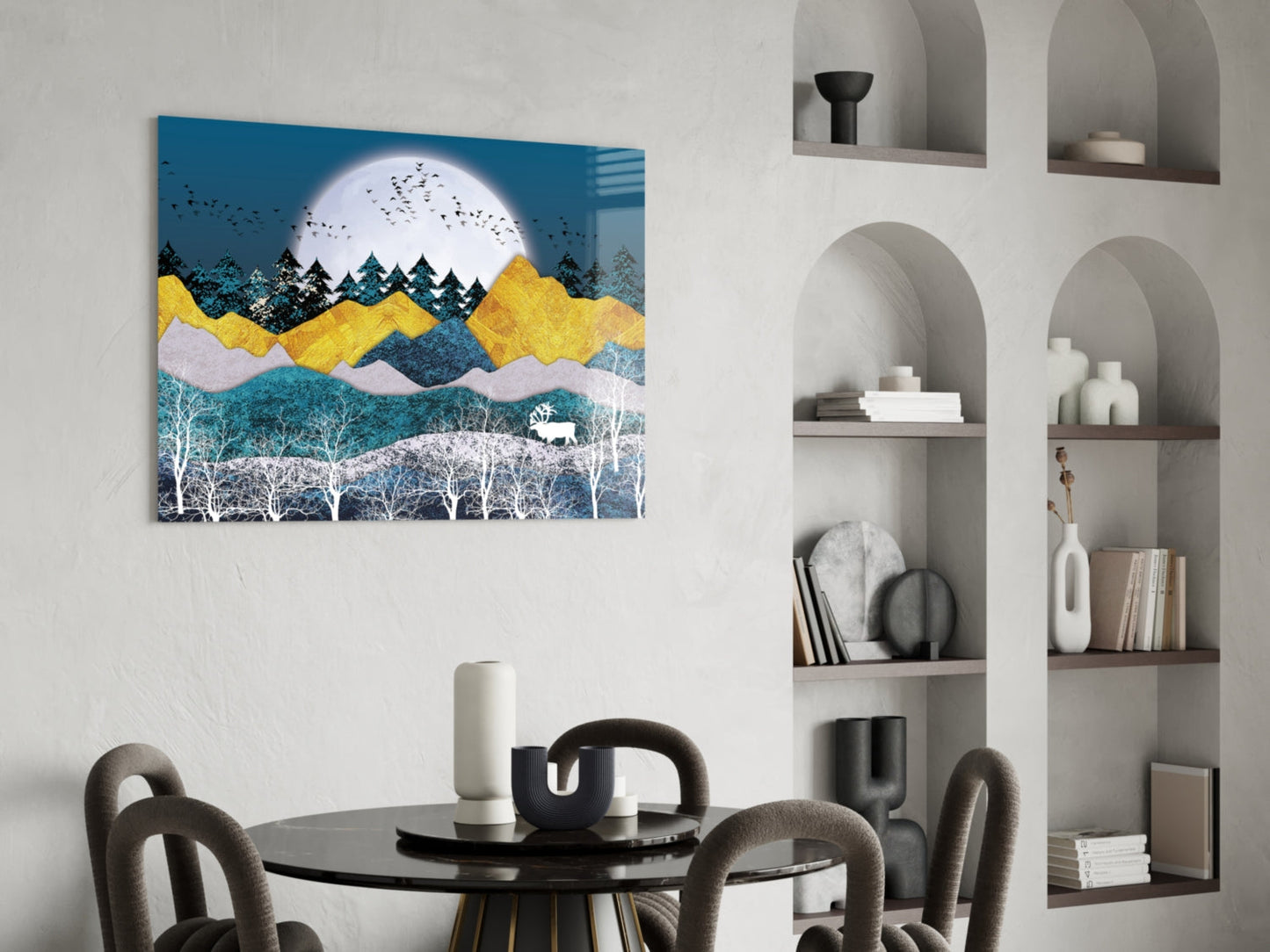Colorful landscape glass wall art featuring blue sky, yellow mountains, white moon, and forest trees displayed above a round black dining table with chairs.