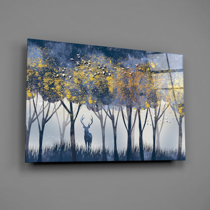 Glass wall art depicting a solitary deer in a misty forest with gold leaf foliage and flying birds against a blue and white background.