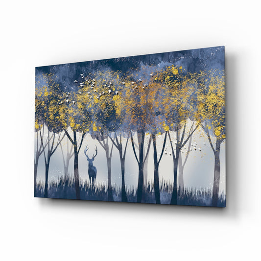 Angled perspective of glass wall art displaying a solitary deer in a blue misty forest with golden foliage and white grass silhouettes.