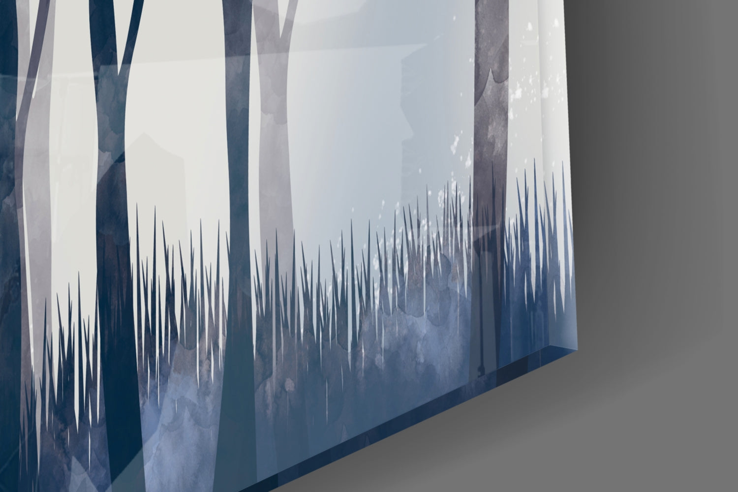 Angled view of glass wall art showing misty forest scene with tall trees and spiky grass silhouettes in blue and white tones.
