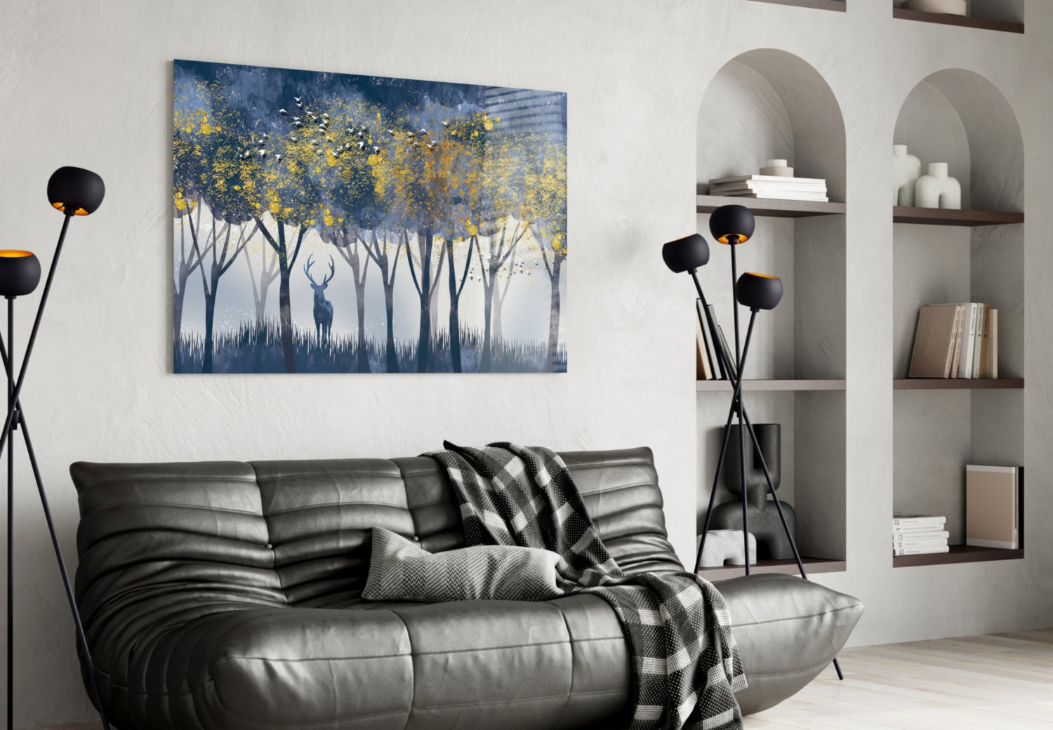 Glass wall art depicting a deer in a blue forest with yellow foliage, displayed above a black leather sofa in a modern living room.