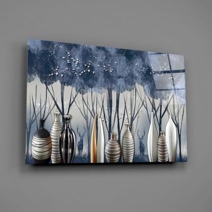 Glass wall art featuring decorative vases in white, striped, and black finishes against a blue forest landscape with deer silhouettes and flying birds.