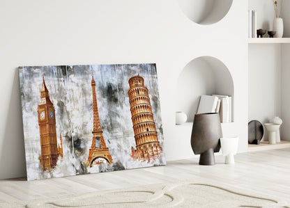 Glass wall art featuring Big Ben, Eiffel Tower, and Leaning Tower of Pisa in golden tones leaning against white wall with decorative objects.