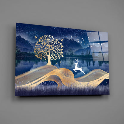 Glass wall art featuring gold tree and deer against blue mountain lake landscape, angled view showing glass panel construction.