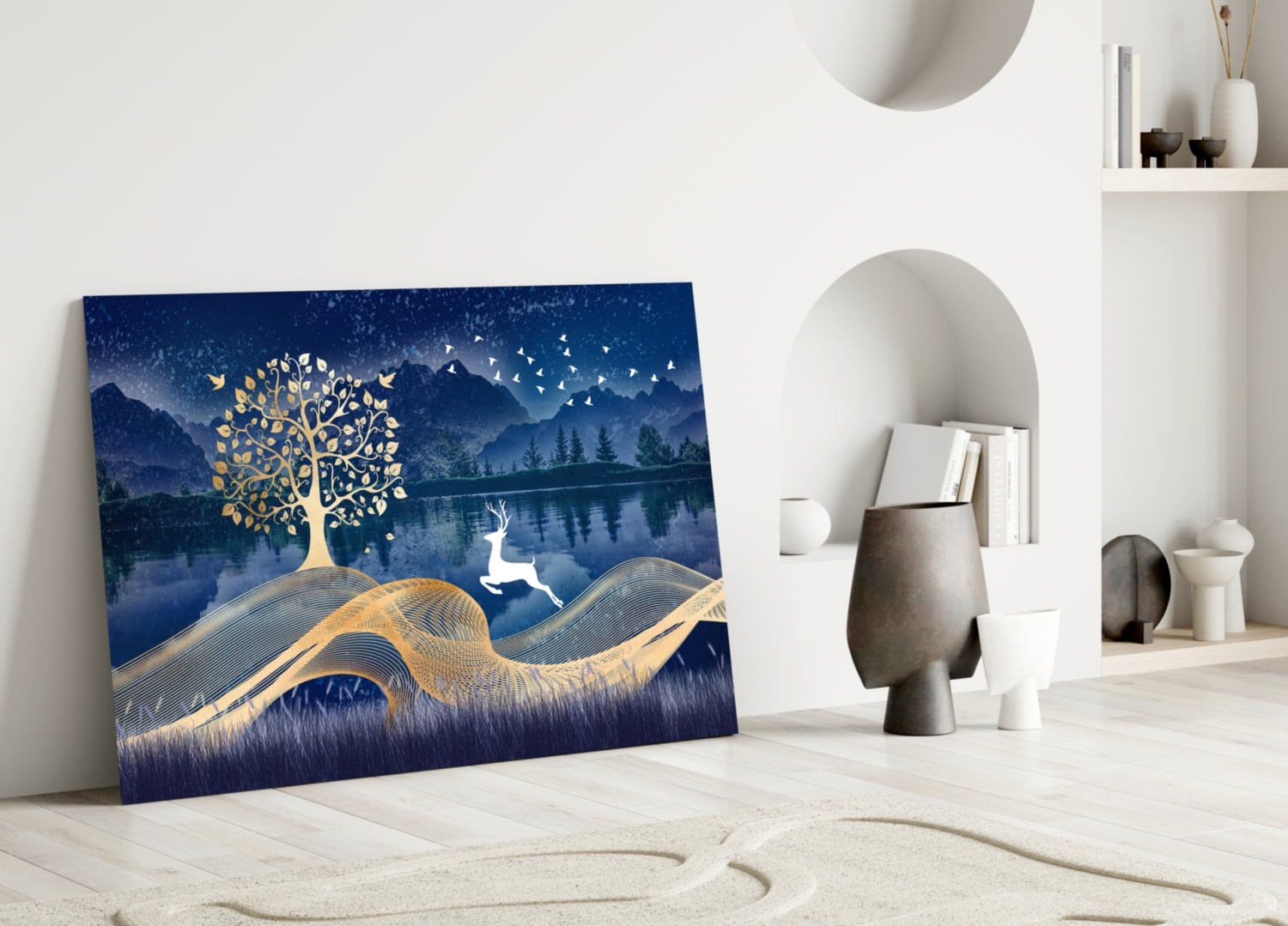 Magic Deer Glass Wall Art leaning against white wall in minimalist room setting, displaying gold tree and leaping deer on deep blue landscape background.