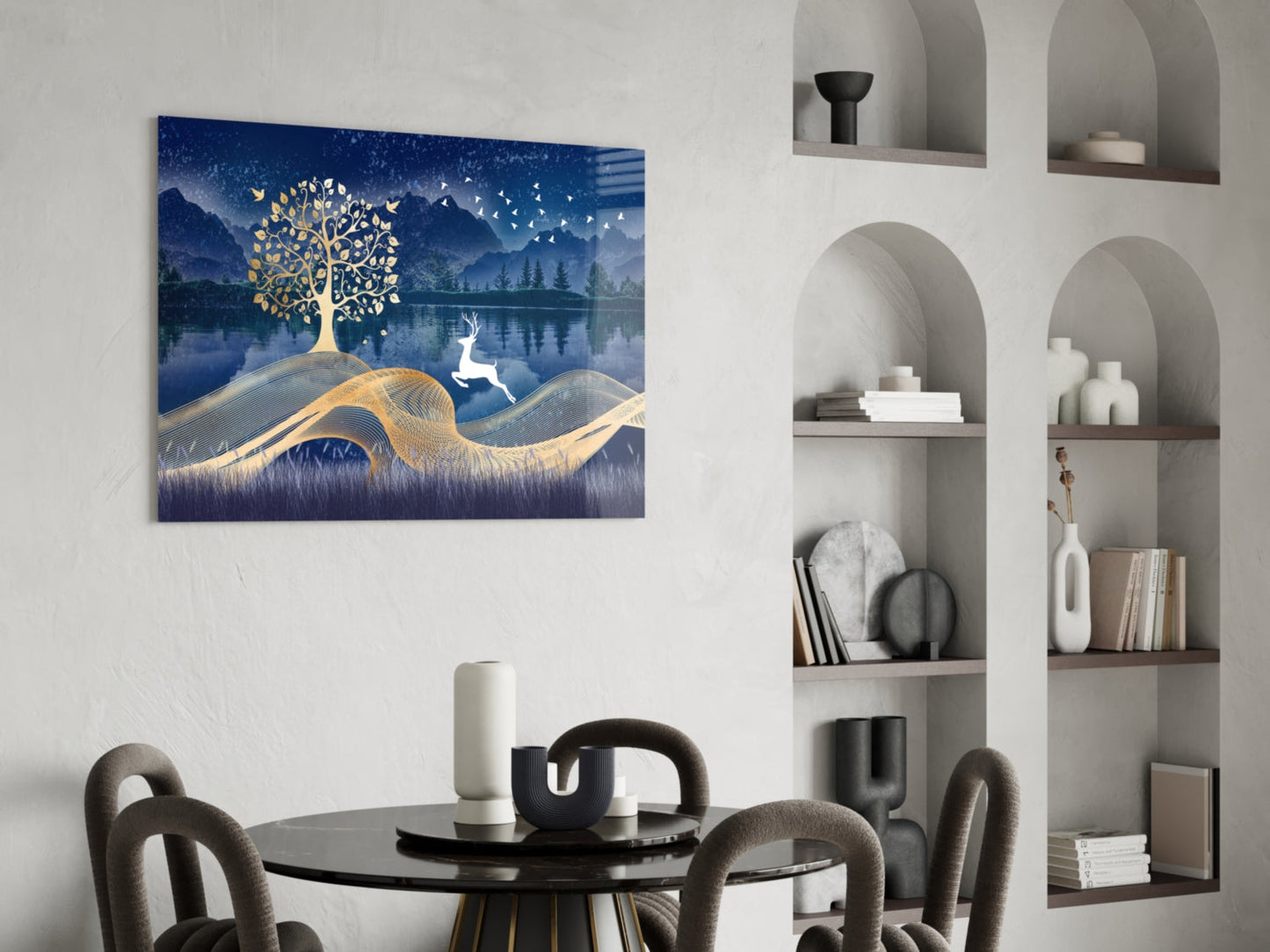 Magic Deer Glass Wall Art displayed above a round black dining table in a modern interior with arched wall shelving, showing gold tree and white deer on deep blue landscape background.
