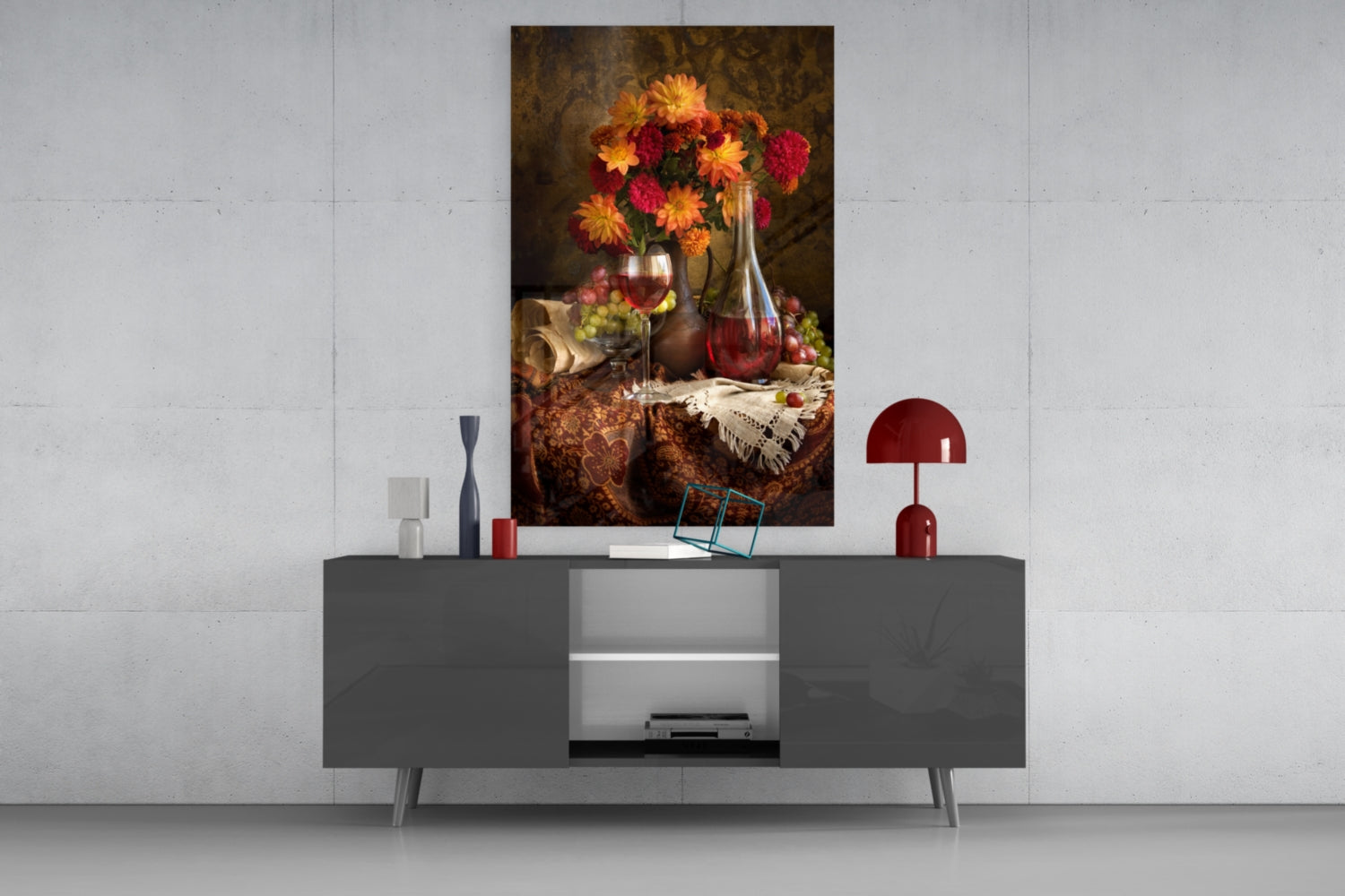 Glass wall art featuring vibrant orange and red flowers in vase with wine bottle and grapes, displayed above modern gray console table.