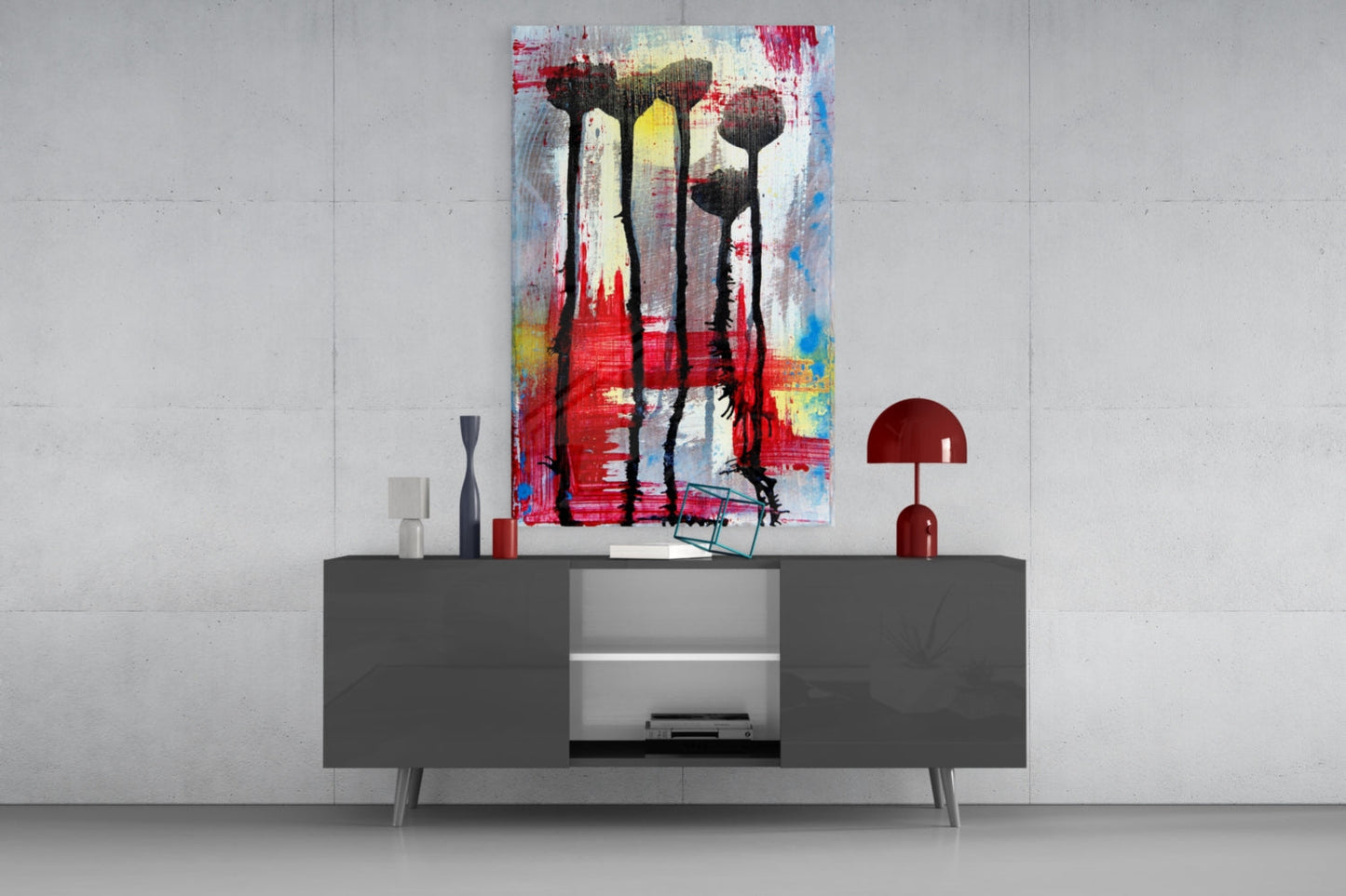 Colorful glass wall art with abstract flower silhouettes in red, yellow, and blue displayed above a dark console table in a modern interior setting.