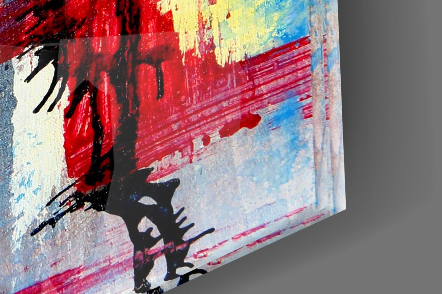 Close-up angled view of glass art showing black silhouetted flower design against red, yellow, and blue brushstroke background.