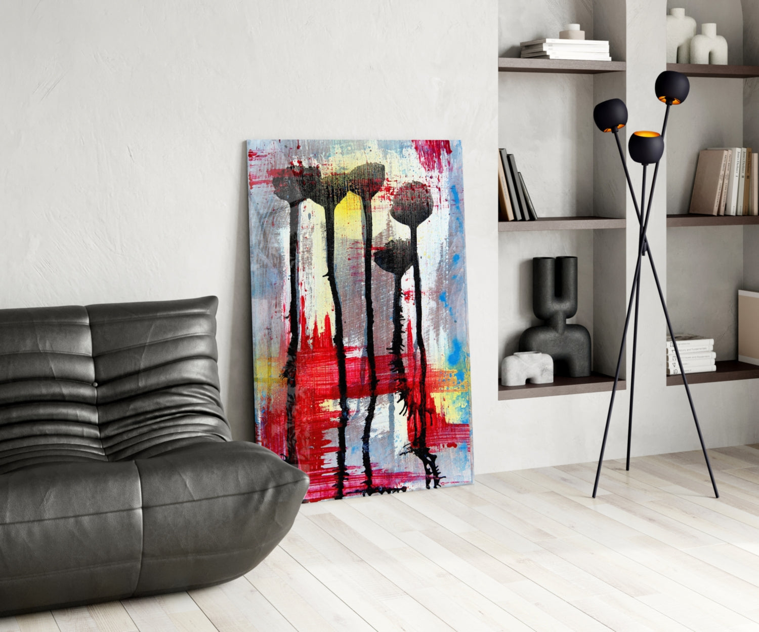 Colorful abstract glass art with black flower silhouettes displayed in modern living room beside gray leather chair and floor lamp.