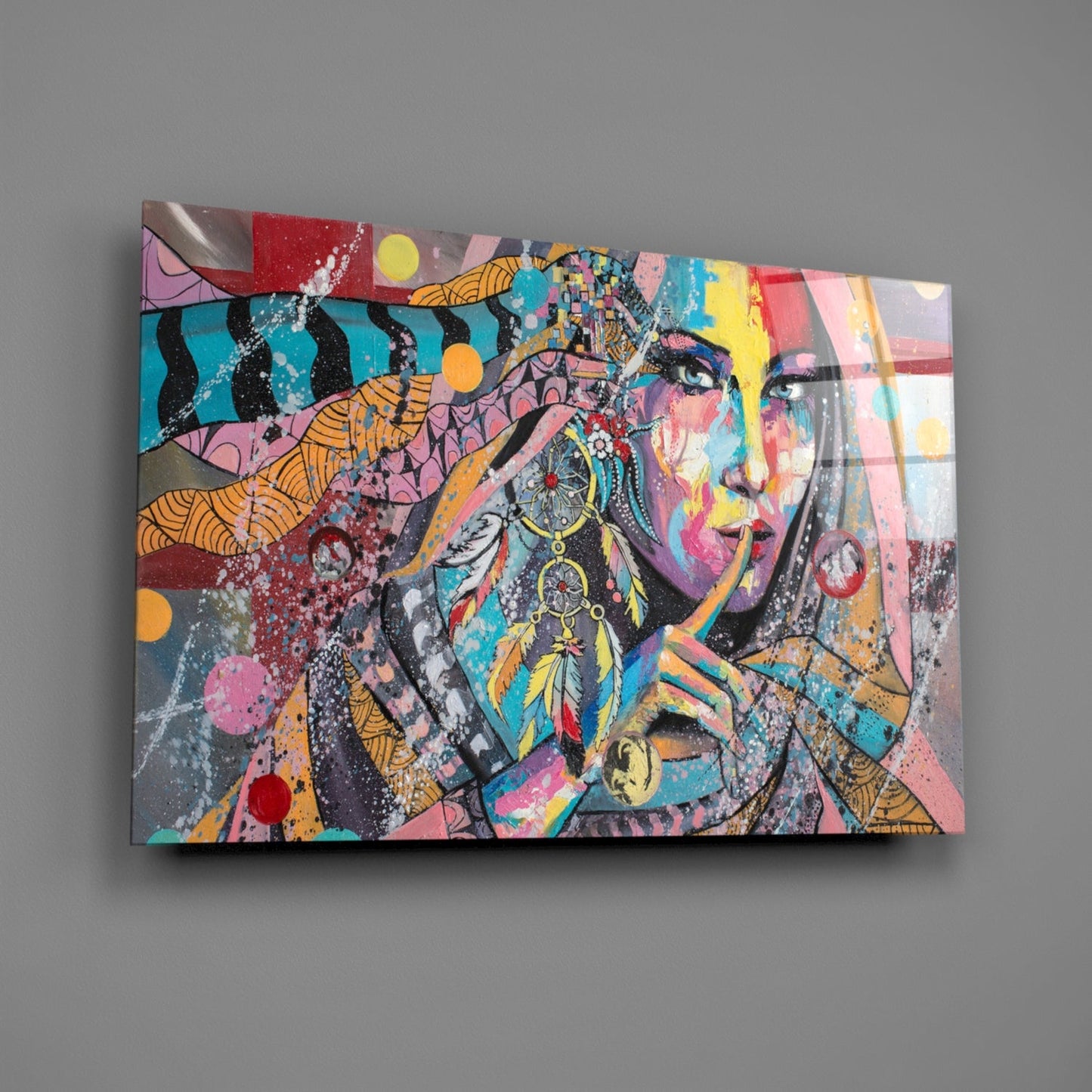 Colorful glass wall art featuring a stylized woman's face with feather earrings, geometric patterns, and vibrant splashes of pink, turquoise, yellow, and orange.