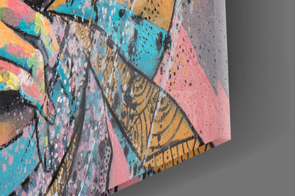 Close-up detail of colorful glass wall art showing textured surface with pink, turquoise, yellow, and black painted sections on canvas edge.