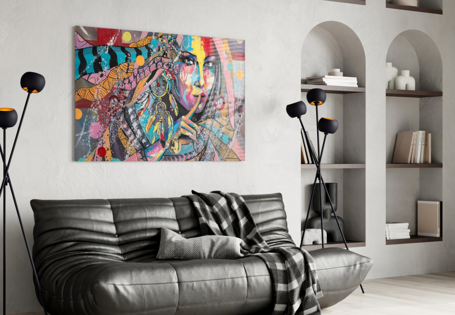 Colorful abstract portrait glass wall art hung above black leather sofa in modern living room with arched shelving.