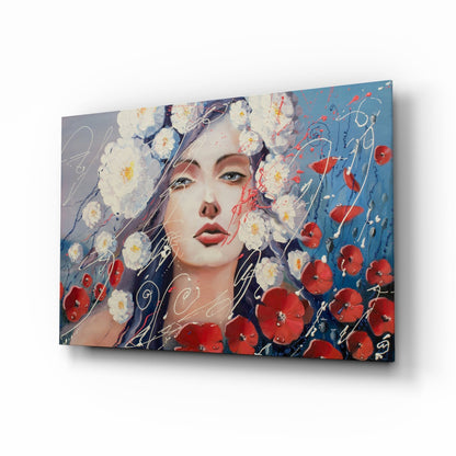 Angled view of glass wall art featuring a woman's face surrounded by white daisies and red poppies against a blue gradient background with decorative line drawings.