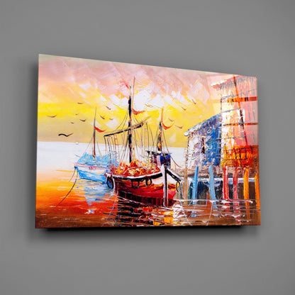 Angled view of glass wall art depicting a red sailing ship at sunset dock with yellow sky and blue water reflections.
