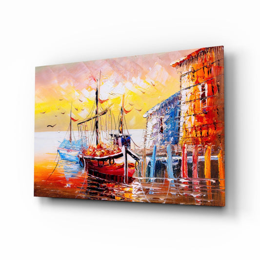Angled view of glass wall art depicting a red sailing boat at sunset dock with colorful buildings, vibrant yellows and oranges dominating the scene.