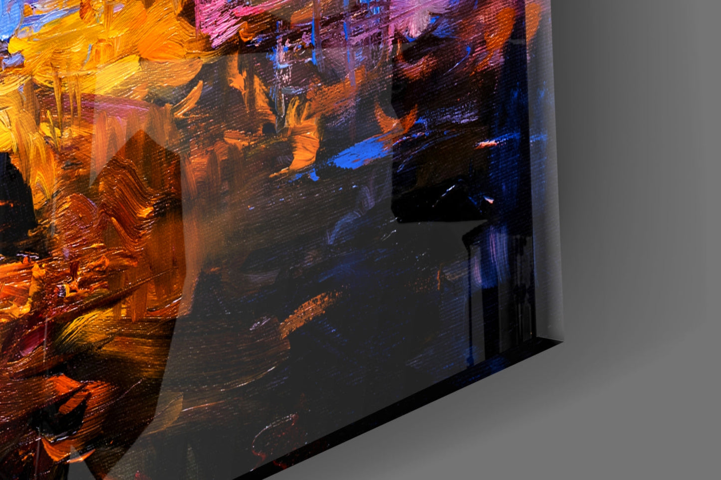 Angled side view of Dark Blue Sunset Glass Wall Art displaying vibrant orange, yellow, pink, and blue brushstrokes on black glass panel.