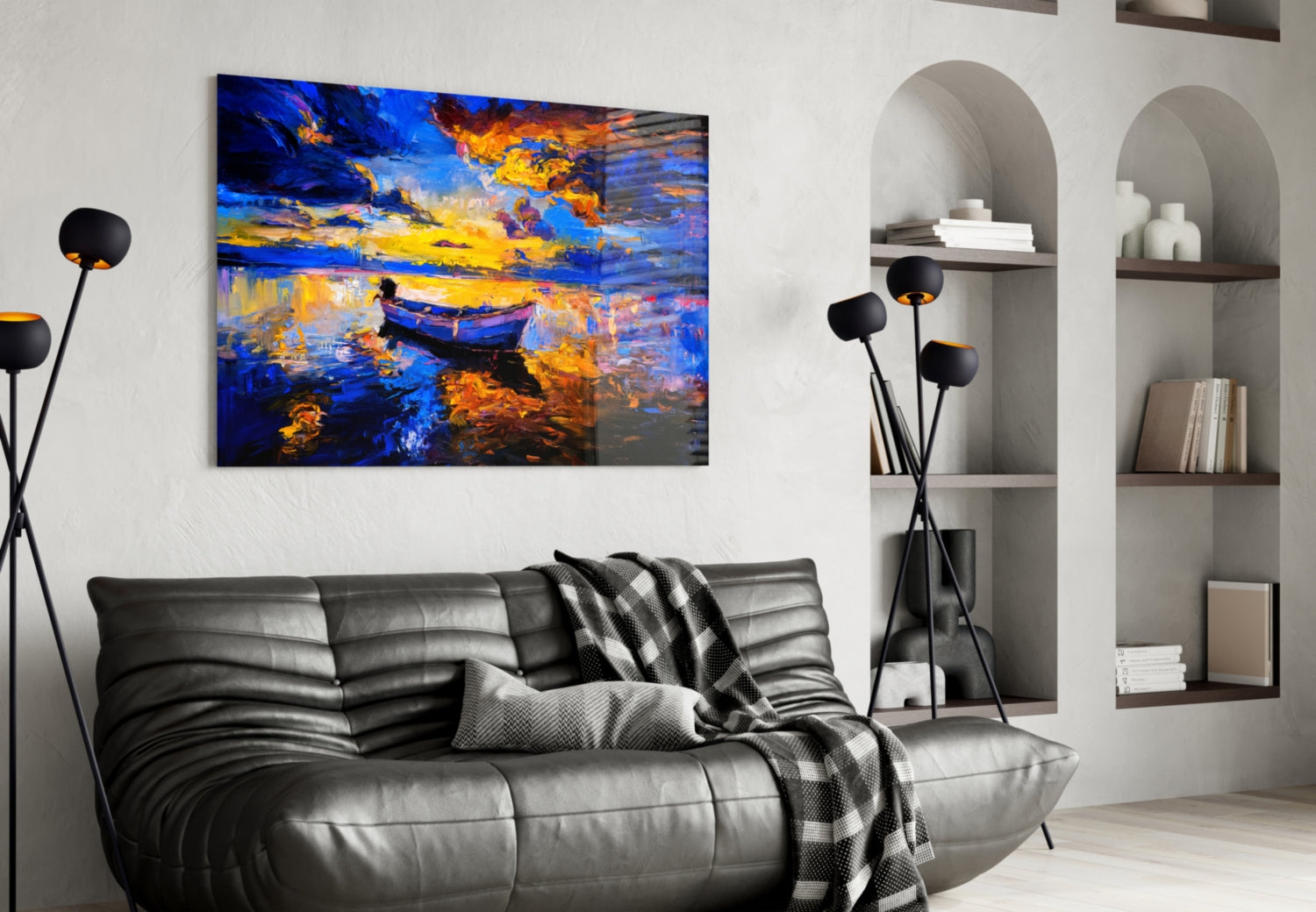 Dark blue sunset glass wall art depicting a golden-lit boat on water, displayed above a black leather sofa in a modern living room.