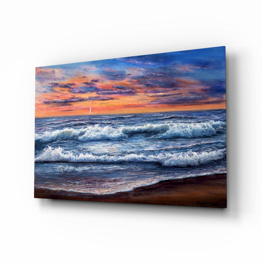 Angled view of glass wall art displaying a beach sunset scene with orange sky, rolling white-capped waves, and sandy shoreline with sailboat on horizon.