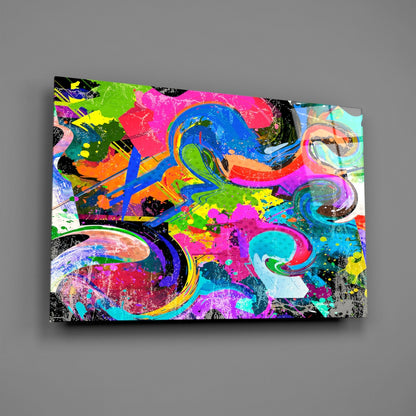 Colorful abstract Ebruli glass wall art featuring vibrant swirls of pink, blue, green, yellow, and black paint splatters on a rectangular panel displayed against a gray background.
